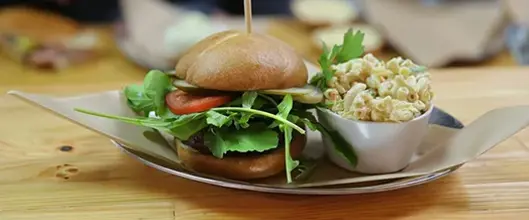 A plate holding a burger and a side of mac and cheese.